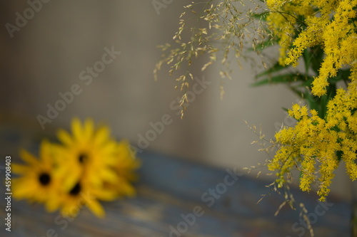 Solidago and poa grass bouquet on bokeh vintage, background with blurr rudbeckia flowers, floral, botanic background with space for text, autumn image with yellow flowers. photo