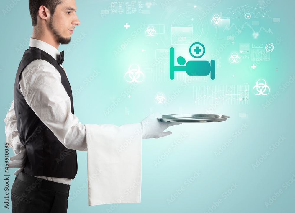Handsome young waiter in tuxedo holding healthcare icons on tray Handsome young waiter in tuxedo holding healthcare icons on tray