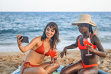 Happy girlfriends taking selfie on beach