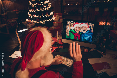 Photo of sweet pretty mature man dressed santa costume speaking modern gadget waving arm indoors home room