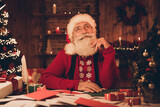 Photo of aged santa claus happy positive smile hand touch beard think dream enjoy eve time noel decoration atmosphere indoors