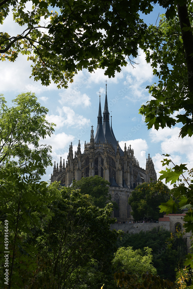 Obraz premium Church of St. Barbara Kutná Hora, trees in foreground, on a cloudy day