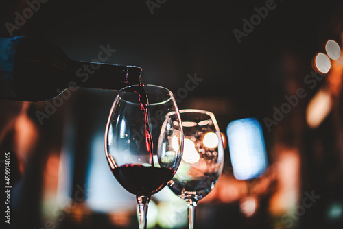 waiter pouring red wine into a glass in cafe or bar photo