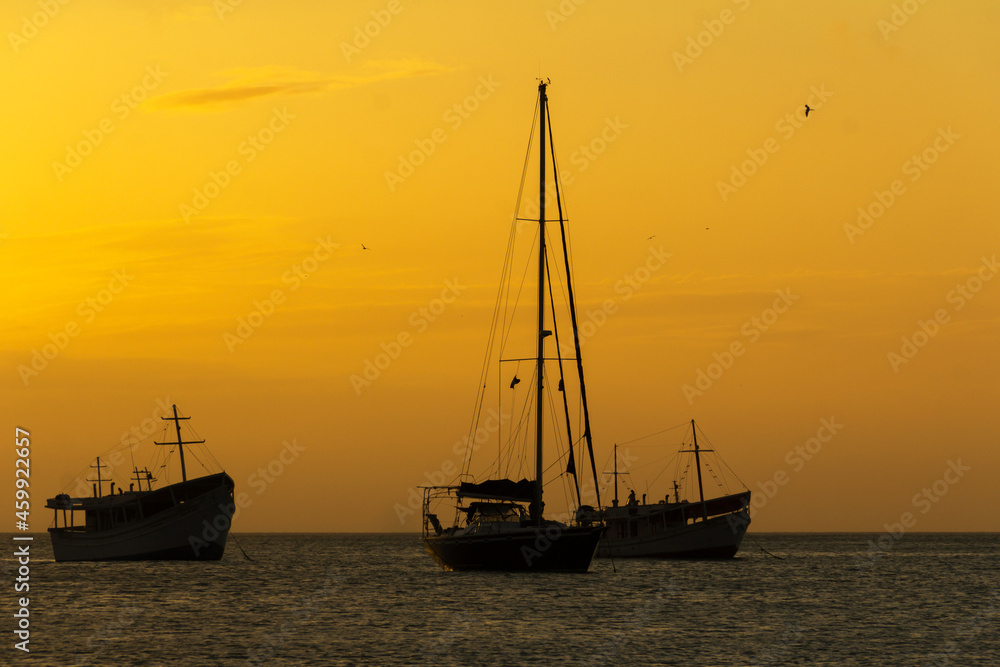 Boats at sea, backlit, at sunset time