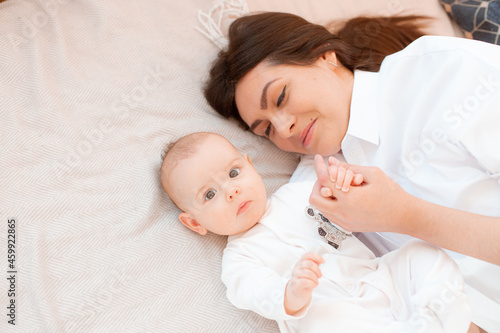 mom and baby are lying on the bed in the bedroom