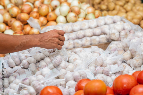 mano de un hombre en una verdulería comprando ajos