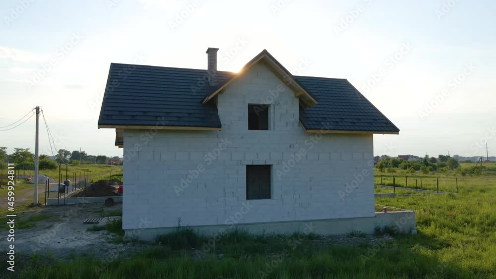 Unfinished frame of private house with aerated lightweight concrete walls and metal rooftop under construction. Unfinished frame of private house with aerated lightweight concrete walls and metal rooftop under construction.