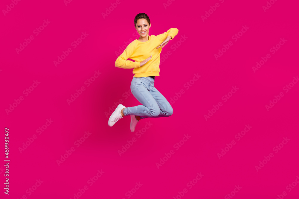 Photo of excited pretty young lady wear yellow jumper smiling jumping high isolated pink color background