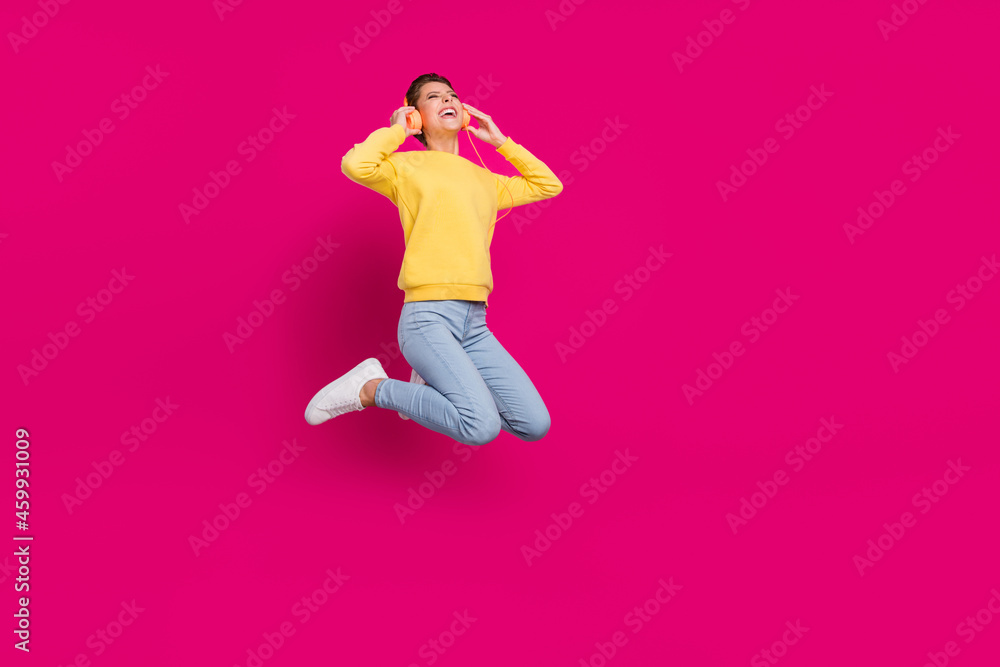 Photo of pretty charming young woman dressed yellow pullover jumping listening music isolated pink color background