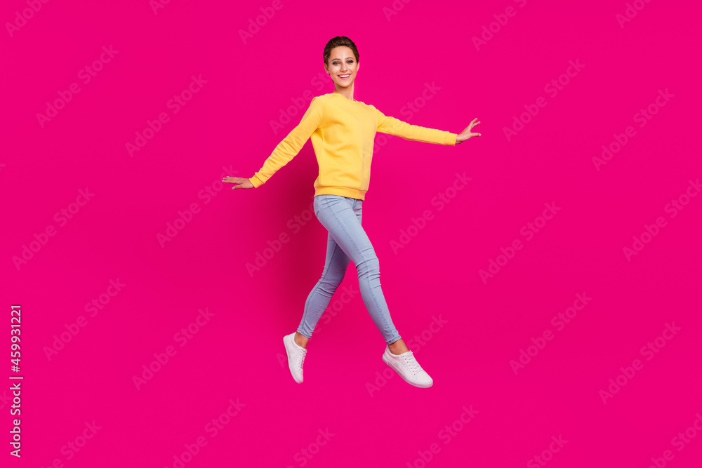 Photo of sweet pretty young lady wear yellow jumper smiling jumping walking isolated pink color background