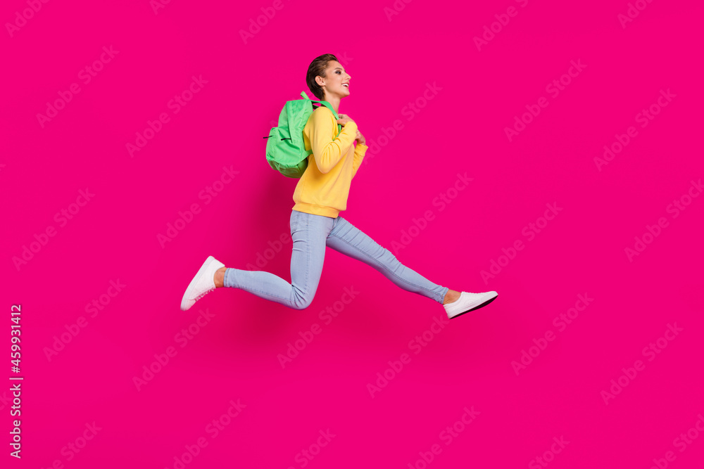 Photo of shiny charming young lady wear yellow jumper rucksack jumping running looking empty space isolated pink color background