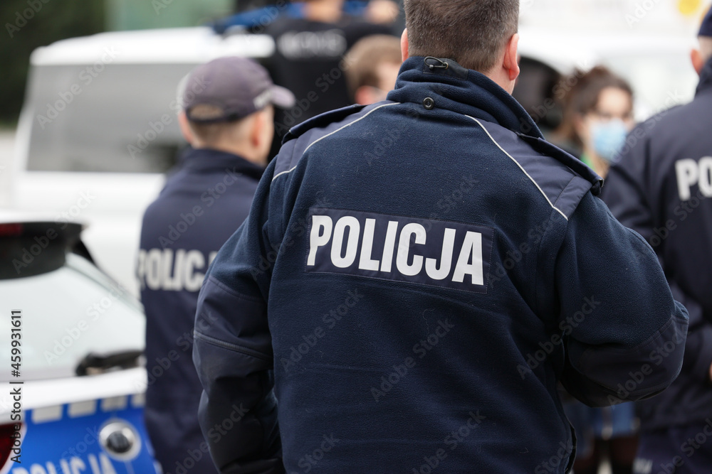 Polscy policjanci w niebieskim mundurze na zabezpieczeniu imprezy w mieście. - obrazy, fototapety, plakaty 