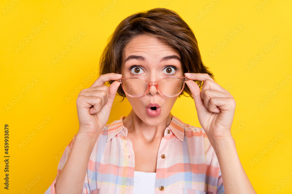 Photo of amazed shocked young woman reaction information wear glasses news isolated on yellow color background Photo of amazed shocked young woman reaction information wear glasses news isolated on yellow color background