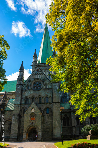 Nidaros Cathedral, (Nidarosdomen) Trondheim Norway framed by green trees with blue sky background