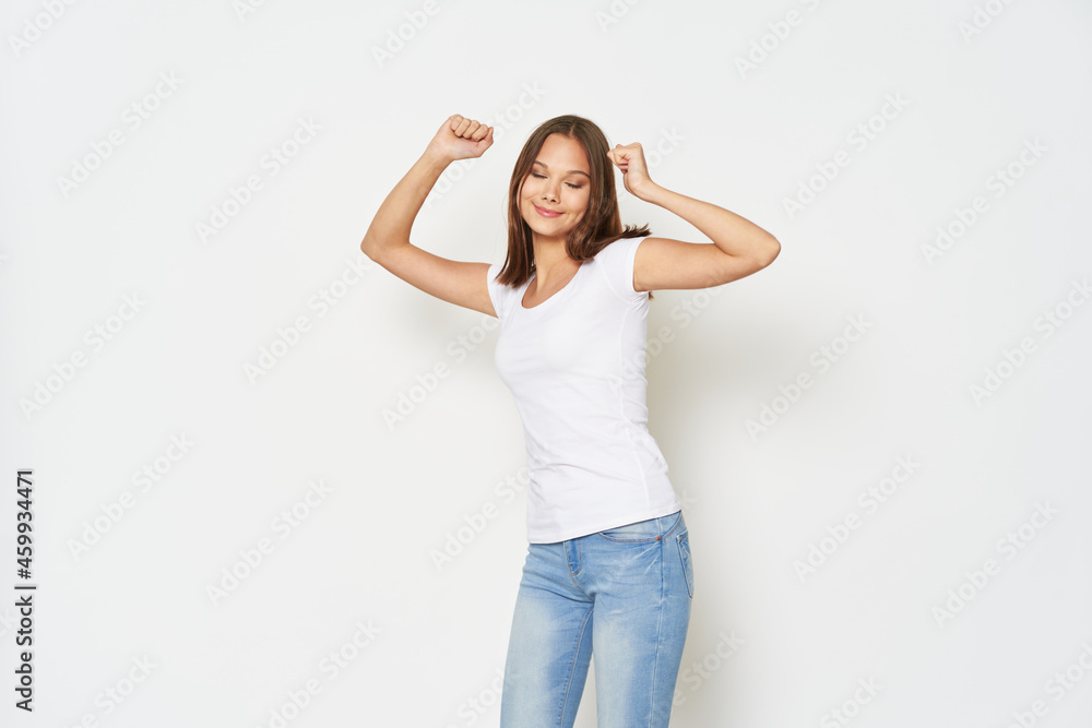 young woman in a white t-shirt gestures with her hands on a light background jeans model young woman in a white t-shirt gestures with her hands on a light background jeans model