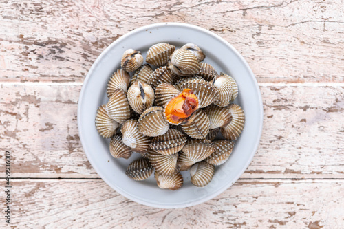 fresh steamed cockles, boiled cockles in ceramic plate on old white wood texture background, top view, light and airy food photography, blood cockle photo