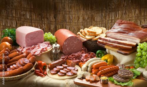 Composição com produtos embutidos, linguiça, bacon, presunto, salsichas em mesa rústica.