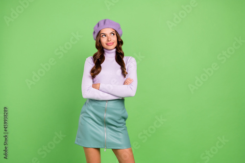 Photo of adorable minded person folded arms look interested empty space isolated on green color background © deagreez