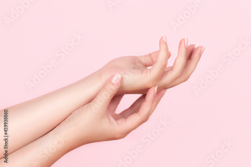 Female hands with beautiful manicure - pink nude nails on pink background. Nail care concept