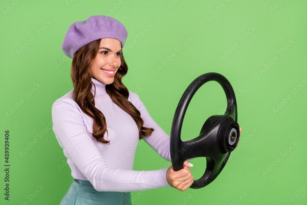 Profile portrait of pretty positive girl arms hold wheel look empty space isolated on green color background Profile portrait of pretty positive girl arms hold wheel look empty space isolated on green color background