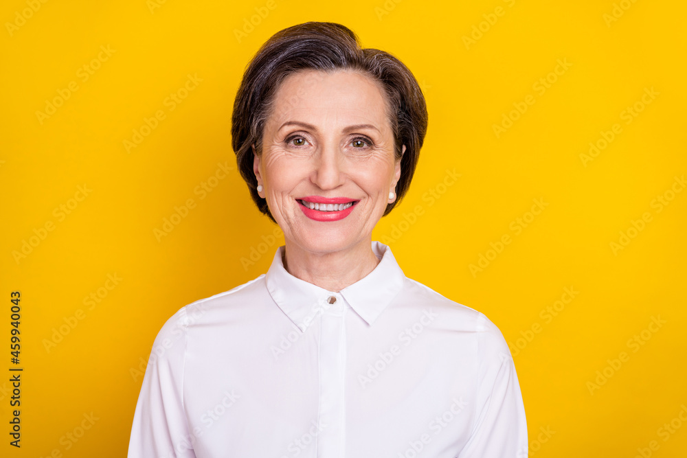 Photo of adorable shiny mature lady wear white clothes smiling isolated yellow color background Photo of adorable shiny mature lady wear white clothes smiling isolated yellow color background