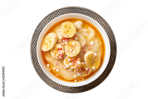 Semolina porridge with syrup and banana in a bowl isolated on a white background. Sweet breakfast, baby food.