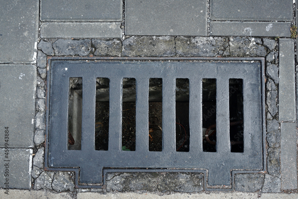 Grille of the drainage system on the pedestrian sidewalk.             