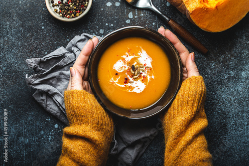 Female hands with bowl of pumpkin soup photo