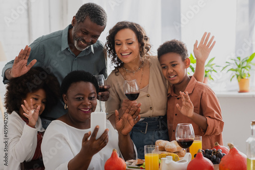 Smiling african american family taking selfie on smartphone during thanksgiving celebration