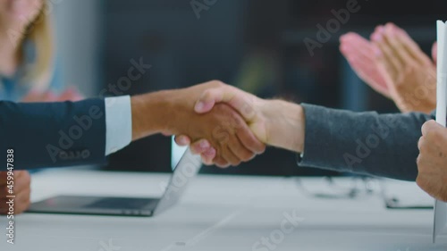 Cropped view of man holding just signed business agreement and shaking hand of business partner. Modern open space office interior. photo