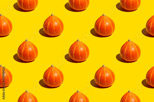 Seamless pattern of ripe juicy whole autumn orange pumpkins on yellow background