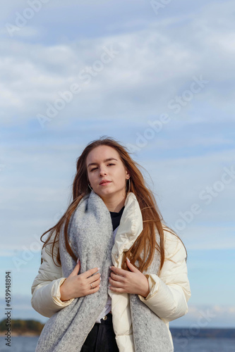 a girl in a light jacket and with a gray scarf on the bank of the Volga