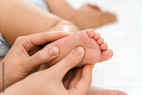 Mom does a foot massage for a sleeping baby  mom s hands gently massage the newborn foot