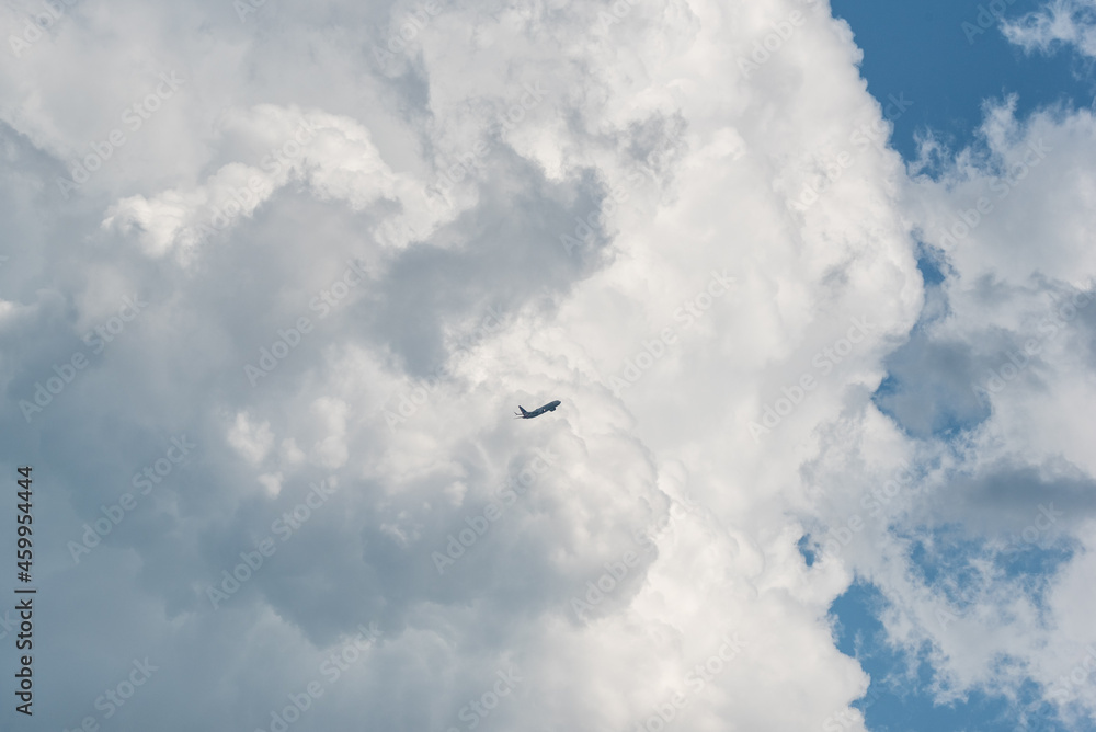 Airplane in the distance flying past a large cloud