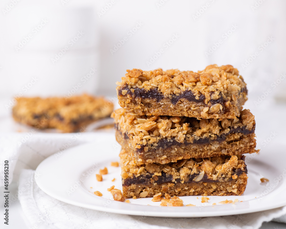 Date squares (or Matrimonial cake) stacked on a plate in a white kitchen Date squares (or Matrimonial cake) stacked on a plate in a white kitchen