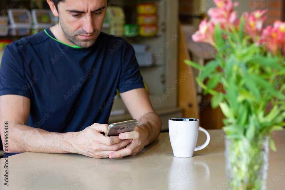 Man with cellphone on table and coffee cup and flower vase on sides. Stressful lifestyle, busy business work, nervous concepts Man with cellphone on table and coffee cup and flower vase on sides. Stressful lifestyle, busy business work, nervous concepts