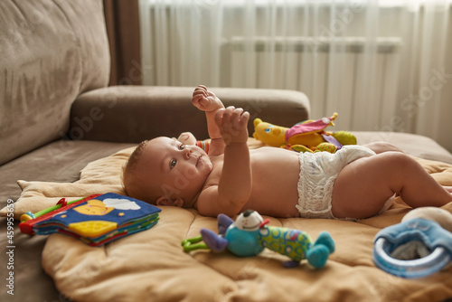 Young child training physical range of motion, lying on sofa photo