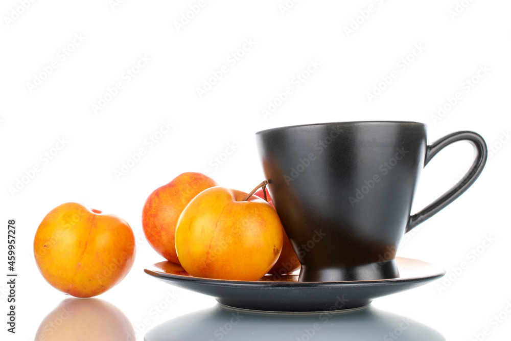 Several juicy organic yellow-red plums on a saucer with a black cup, close-up, isolated on white. Several juicy organic yellow-red plums on a saucer with a black cup, close-up, isolated on white.
