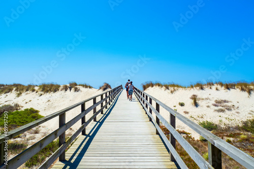 Turistas caminando por una pasarela de madera entre las dunas de la playa de Aveiro
