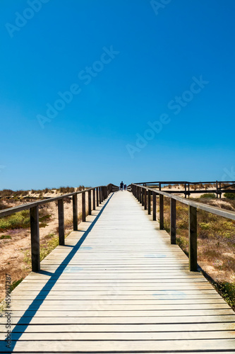 Turistas caminando por una pasarela de madera entre las dunas de la playa de Aveiro