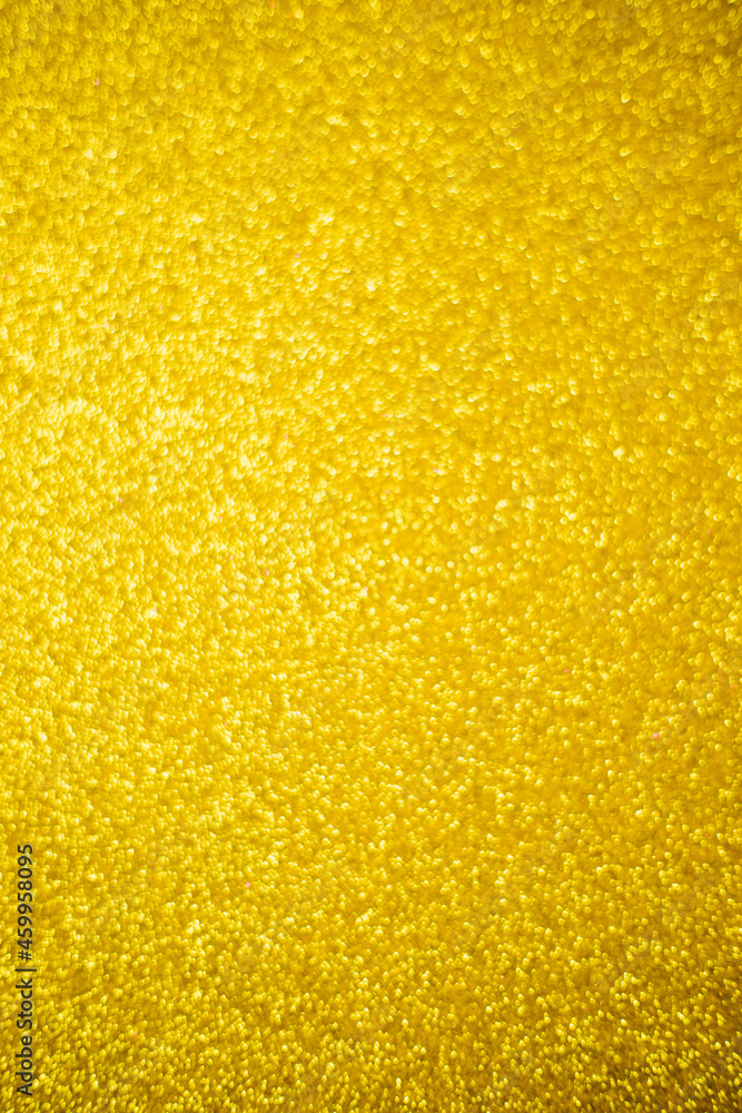 Blurry shimmering background of gold-colored sequins. Light abstract bokeh texture.Sparkling wallpaper for Christmas.