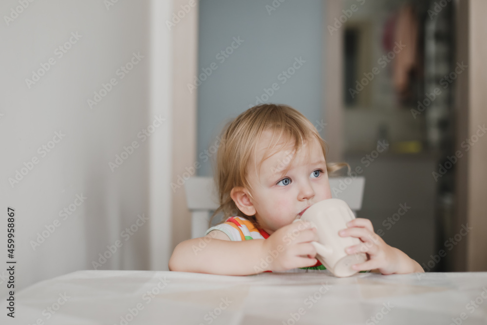 funny little girl drinking milk sitting in the kitchen funny little girl drinking milk sitting in the kitchen