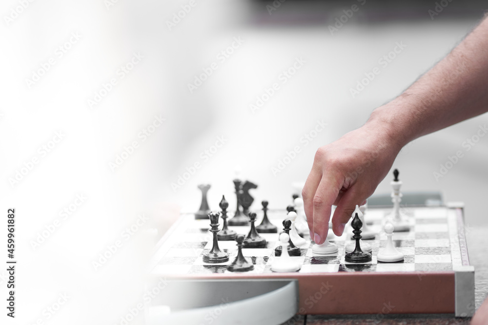Fototapeta premium The hand of one of the men playing chess. Chess board game concept of business ideas and competition and strategic plan the meaning of success. High quality photo