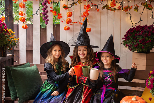 Happy Halloween! Three cute laughing girls in witch costumes are celebrating Halloween.
