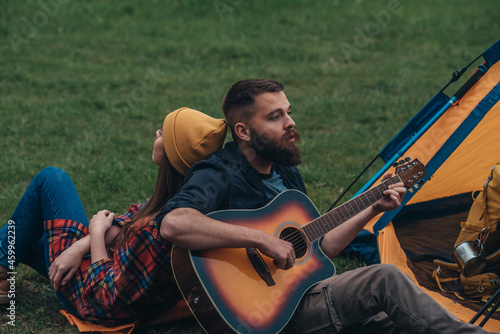 Campers playing guitar while having fun in the nature