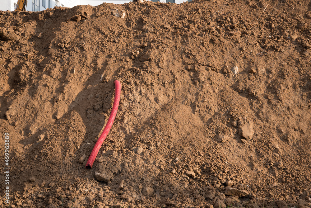 Sewer pipe removed from the ground during the construction phase. Cable channel, taken out from under the building under construction. Construction site. Red corrugated pipe Sewer pipe removed from the ground during the construction phase. Cable channel, taken out from under the building under construction. Construction site. Red corrugated pipe
