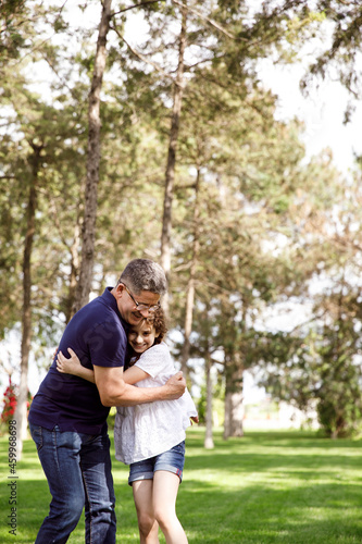 Grandpa hugs his niece in the park on a sunny day.