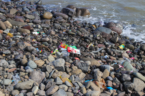 Trash and pollution on the dirty rocky beach