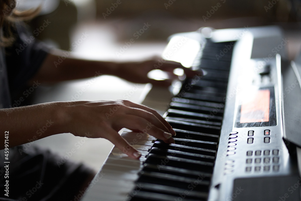 Obraz premium The musician's hands on the synthesizer. A cropped image of a person playing a synthesizer. Side view. High quality photo