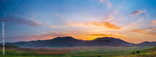 Beautiful sunset sky at Castelluccio di Norcia highlands, Italy. Blooming cultivated fields, famous colourful flowering plain in the Apennines. Agriculture of lentil crops.